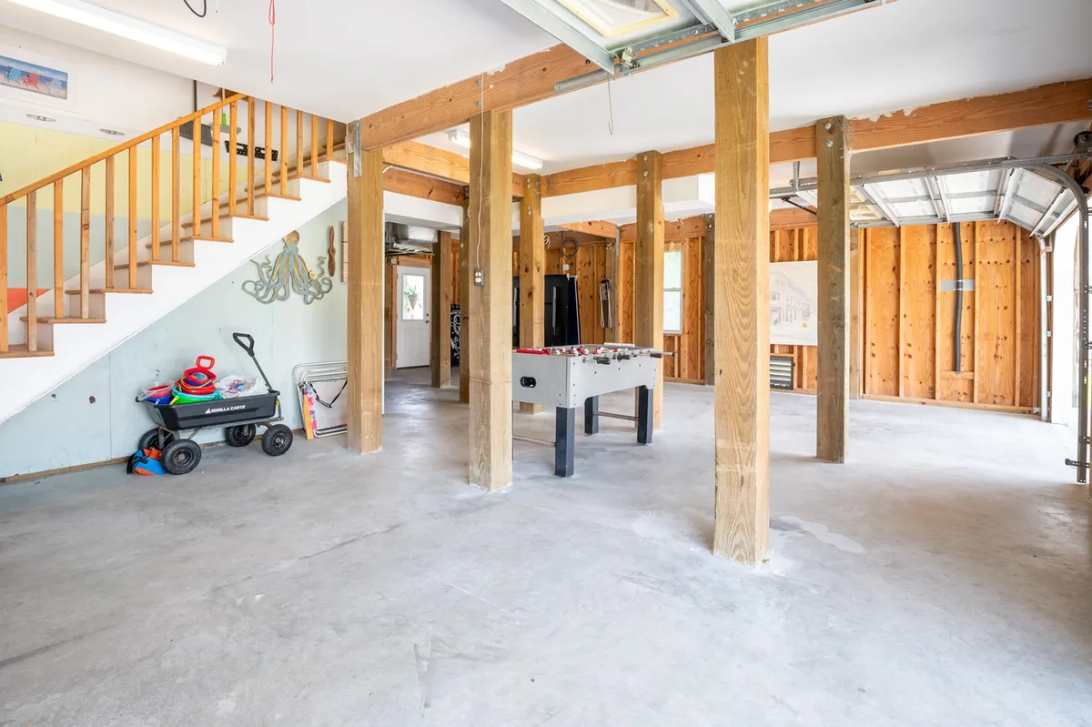 A playful interior scene featuring a foosball table, visible staircase, and garage door. The space is styled for relaxation and lively games, ideal for families looking to unwind with friendly competition.
