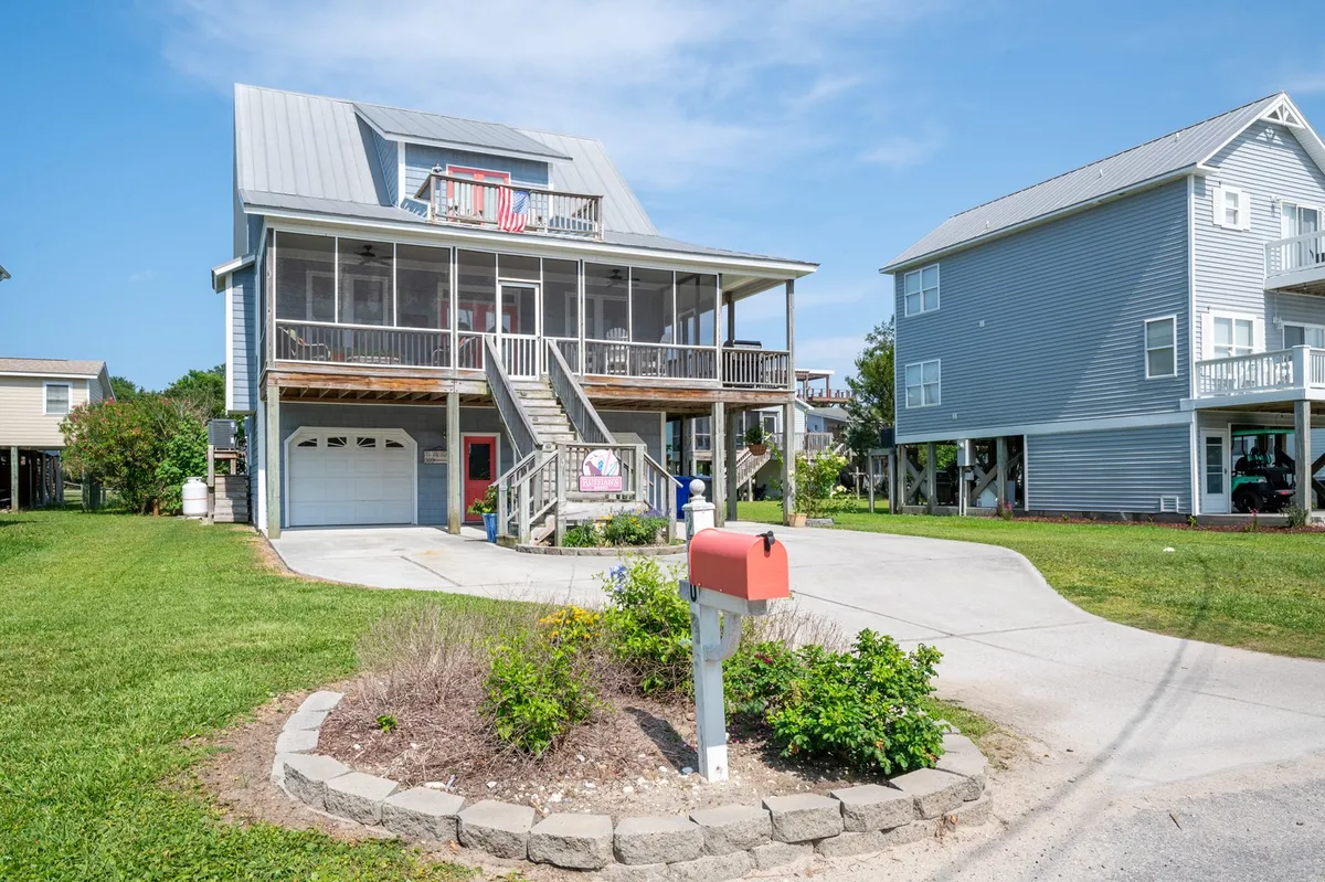 A welcoming exterior shot of the property showing the house with a comfortable porch, landscaped garden, and inviting entrance. The scene suggests a friendly, homey environment perfect for family gatherings and outdoor relaxation.